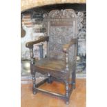 AN ANTIQUE OAK WAINSCOT OPEN ARMCHAIR The carved top rail figured with a facial mask above a
