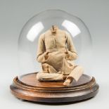A 19TH CENTURY INDIAN CLAY FIGURE UNDER GLASS DOME. Reputed to be unfired to protect the soul of the