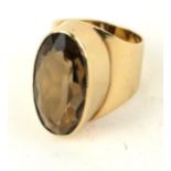 AN EARLY 20TH CENTURY 9CT GOLD AND SMOKY QUARTZ BAND RING The oval faceted cut stone (size N).
