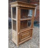 A CONTINENTAL PINE DISPLAY CABINET With a single glazed door above a cupboard. (103cm x 52cm x