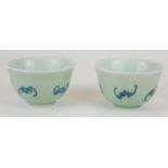 A PAIR OF CHINESE CELEDON GLAZE 'BAT' CUPS Having hand painted underglaze blue bats and square