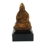 A CHINESE GILT BRONZE BUDDHA Seated pose holding an urn on black perspex base. (Buddha approx 6.7cm)