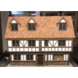 A TUDOR STYLE DOLLS HOUSE With oak beams and floors, wooden furniture, ceramic bathroom suite,