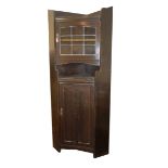 LIBERTY AND CO., LONDON, AN OAK FLOORSTANDING CORNER CABINET Having a single leaded glazed door