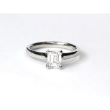 AN 18CT WHITE GOLD AND DIAMOND SOLITAIRE RING The emerald cut stone on a plain gold shank,