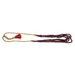 AN INDIAN CARVED RUBY NECKLACE Four strands of graduating beads with gilt wire tassel. (rubies