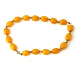 AN EARLY 20TH CENTURY BUTTERSCOTCH AMBER BEAD NECKLACE Having a single row of oval beads with yellow