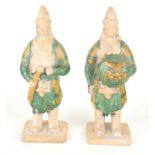 A PAIR OF CHINESE SANCAI GLAZED POTTERY WARRIOR FIGURES Standing pose, clutching a dragon mask