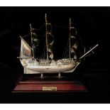 AN ENGLISH SILVER MODEL OF HMS VICTORY On a mahogany stand. (17cm x 14cm)
