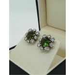 A PAIR OF 18CT WHITE GOLD EARRINGS of floral form, set with central green sapphires surrounded by