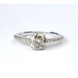 AN 18CT WHITE GOLD AND DIAMOND RING The round cut diamond flanked by diamond set shoulders (size O).