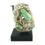 A CHINESE JADE OVAL CARVING OF EXOTIC FRUIT WITH BATS With central pierced decoration, on black
