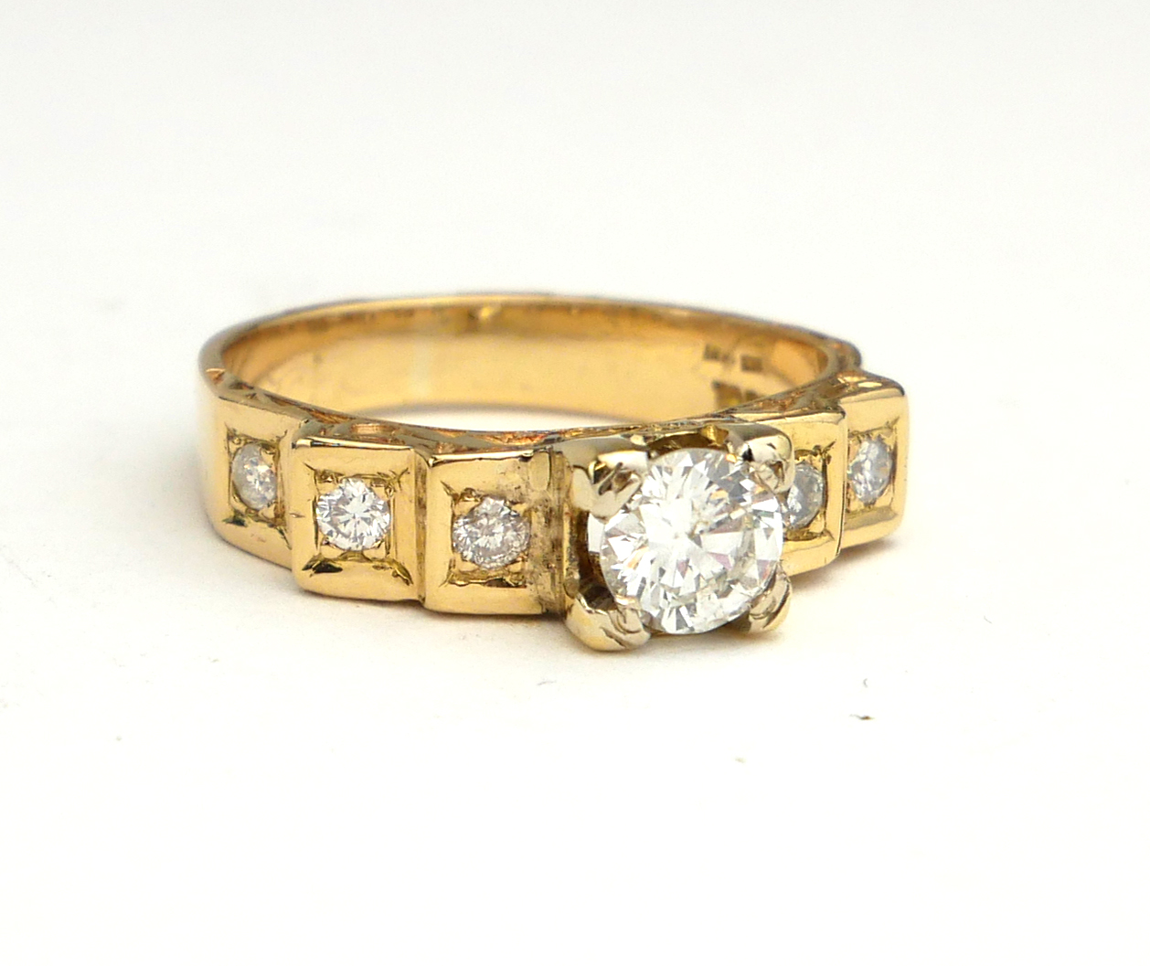 AN 18CT GOLD AND DIAMOND RING The central round cut diamond flanked by diamond set shoulders, in a