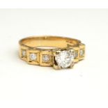 AN 18CT GOLD AND DIAMOND RING The central round cut diamond flanked by diamond set shoulders, in a