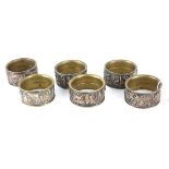 A SET OF SIX VICTORIAN BRASS AND COPPER FIGURAL NAPKIN RINGS With embossed harvesting scenes with