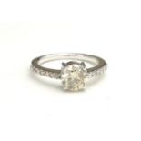 AN 14CT WHITE GOLD AND DIAMOND SOLITAIRE RING The single round cut diamond flanked by diamond set