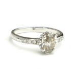 AN 18CT GOLD AND OVAL CUT DIAMOND SOLITAIRE RING Flanked by diamond set shoulders (size N). (