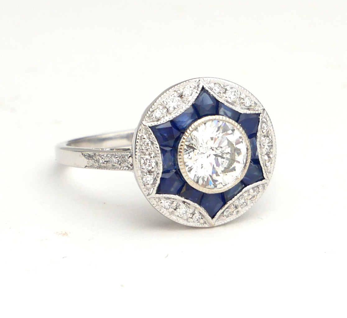 AN 18CT WHITE GOLD, DIAMOND AND SAPPHIRE TARGET RING The single round cut diamond edged with