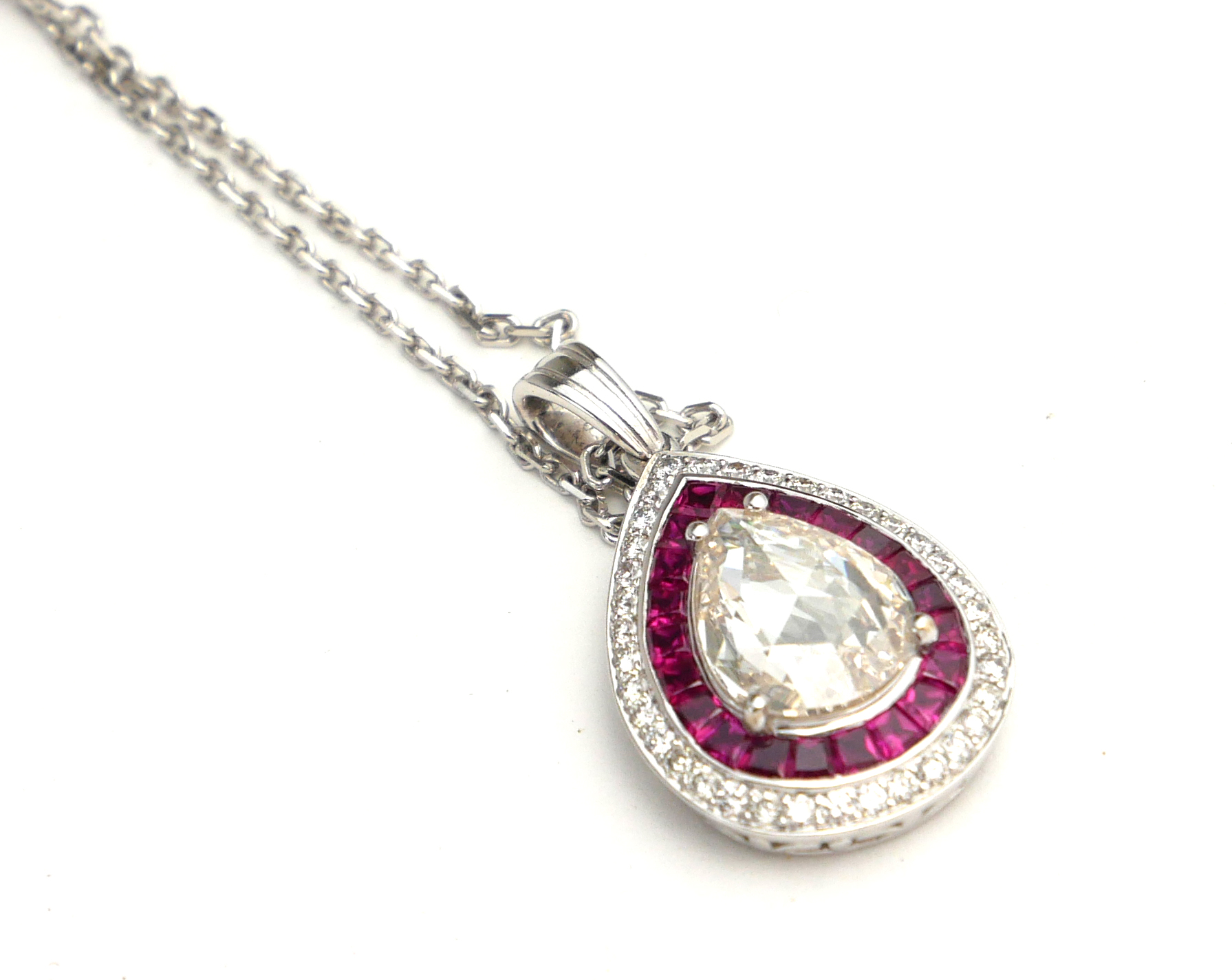 AN 18CT WHITE GOLD DIAMOND AND RUBY PENDANT NECKLACE The central pear cut diamond edged with