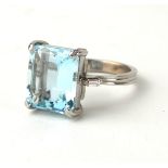 A PLATINUM, DIAMOND AND EMERALD CUT AQUAMARINE COCKTAIL RING (size O). (6.5ct) Condition: good