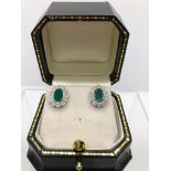 A PAIR OF 18CT WHITE GOLD, EMERALD AND DIAMOND OVAL CLUSTER EARRINGS. (emerald approx 1.66ct,