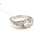 AN 18CT WHITE METAL (TESTS AS GOLD) AND DIAMOND RING The large diamond flanked by diamond