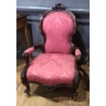 A VICTORIAN MAHOGANY SPOON BACK OPEN ARMCHAIR With carved cartouche, puce fabric upholstery, on