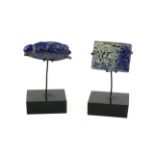 TWO LAPIS LAZULI CARVED PLAQUES Mythical beast and an aquatic scene, on black perspex base. (