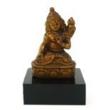 A CHINESE GILT BRONZE BUDDHA Seated pose holding a single flower on lotus base, on black perspex