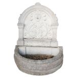 A LARGE DECORATIVE STONE WATER FOUNTAIN With facial mask and foliage decoration above a demilune