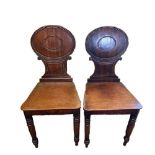 A PAIR OF REGENCY CARVED MAHOGANY HALL CHAIRS The oval backs above solid seats, raised on ring