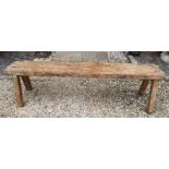 A 19TH CENTURY DISTRESSED COUNTRY PINE BENCH The single plank top, raised on square splayed legs. (