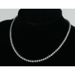 AN 18CT WHITE GOLD AND DIAMOND NECKLACE The single row of round cut diamonds, in a fitted velvet