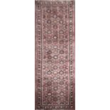AN IRANIAN WOOLLEN RUNNER With floral field on a red ground. (85cm x 236cm)