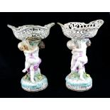 A PAIR OF 19TH CENTURY CONTINENTAL PORCELAIN FIGURAL SWEETMEAT BASKETS Having a pierced basket and