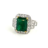 AN 18CT WHITE GOLD EMERALD AND DIAMOND RING, a rectangular cut emerald, edged with diamonds and