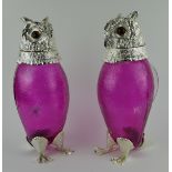 A PAIR OF RUBY GLASS AND SILVER PLATED CARAFES, IN THE FORM OF OWLS With amber glass eyes. (29cm)
