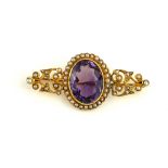 A VICTORIAN YELLOW METAL AMETHYST AND SEED PEARL BROOCH The oval cut amethyst edged with seed pearls