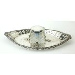 AN EDWARDIAN SILVER AND CUT GLASS OVAL INKWELL With pierced decoration and shell form supports,