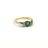 AN EARLY 20TH CENTURY 18CT GOLD, EMERALD AND DIAMOND THREE STONE RING The central oval cut emerald