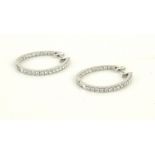 A PAIR OF 18CT WHITE GOLD AND DIAMOND HOOP EARRINGS Oval form set with a row of round cut
