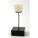 A CARVED INDIAN JADE MINIATURE BOWL Spherical form with fluted base, on black perspex stand. (approx