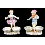 A PAIR OF 20TH CENTURY CONTINENTAL PORCELAIN FIGURAL SALTS Children dancing with two circular dishes