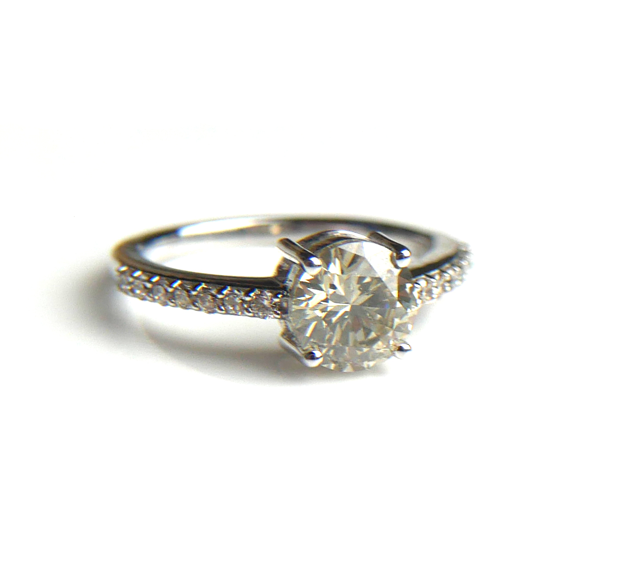AN 18CT WHITE GOLD AND SOLITAIRE DIAMOND RING Flanked by diamond shoulders (size N/O). (approx total