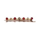 AN EARLY 20TH CENTURY GOLD, DIAMOND AND GARNET SET BAR BROOCH. (length 6cm)