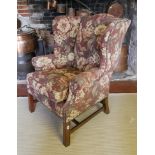 A GEORGIAN STYLE WING ARMCHAIR On chamfered legs, along with a stool. (78cm x 81cm x 98cm)