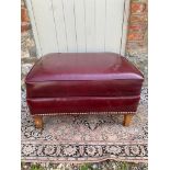 A OXBLOOD FAUX LEATHER UPHOLSTERED FOOTSTOOL With stud work, raised on square tapering legs. (68cm x