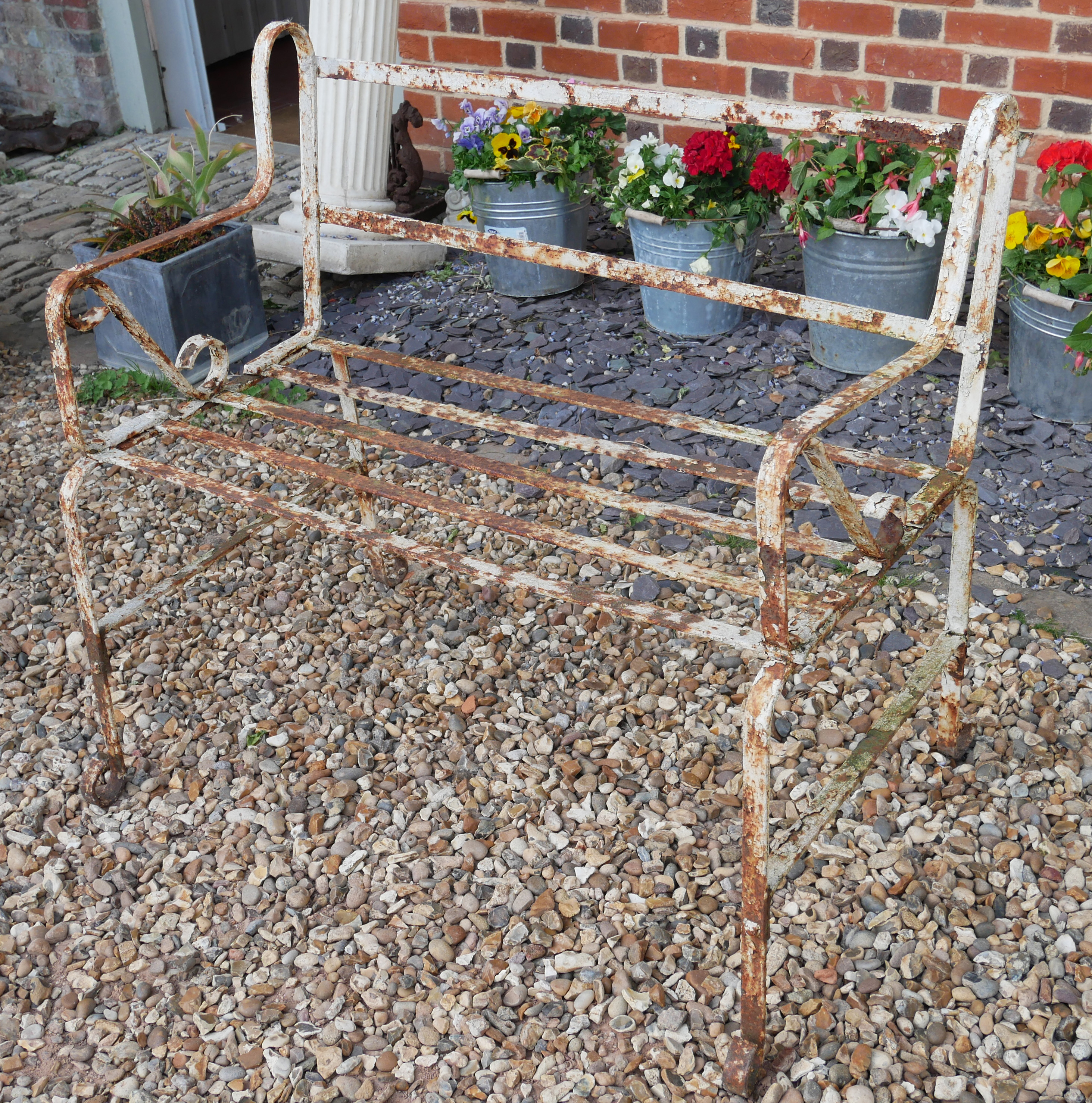 A 19TH CENTURY WROUGHT IRON STRAPWORK GARDEN BENCH Having scrolled arms and white painted finish. (