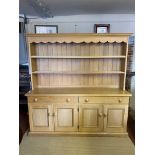A VICTORIAN STYLE LIMED OAK DRESSER With open shelves above two long drawers and four cupboards,