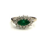 AN 18CT WHITE GOLD AND DIAMOND RING Having a marquise cut emerald edged with round cut diamonds. (